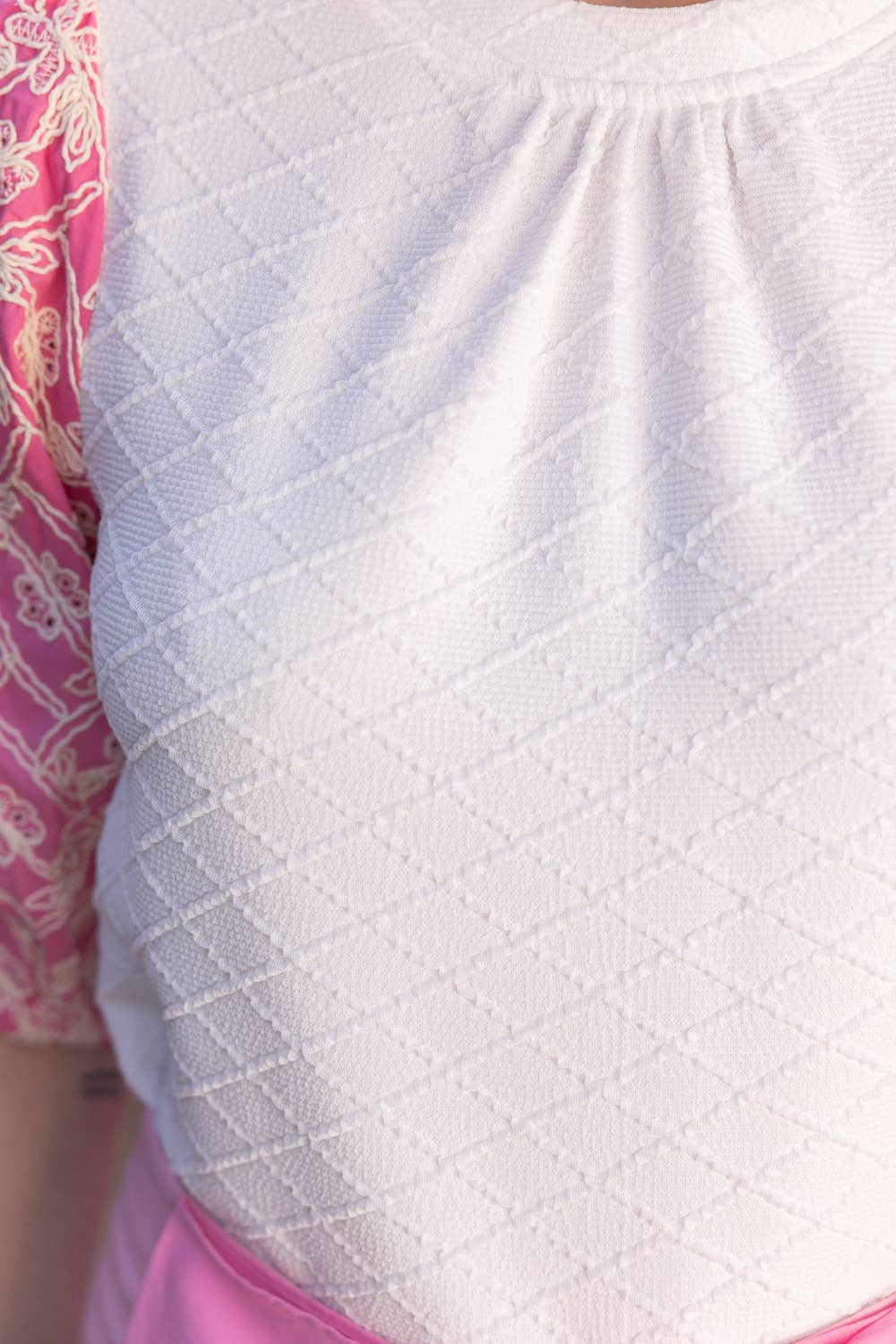 Close-up of a white textured garment with pink and gold patterned fabric.
