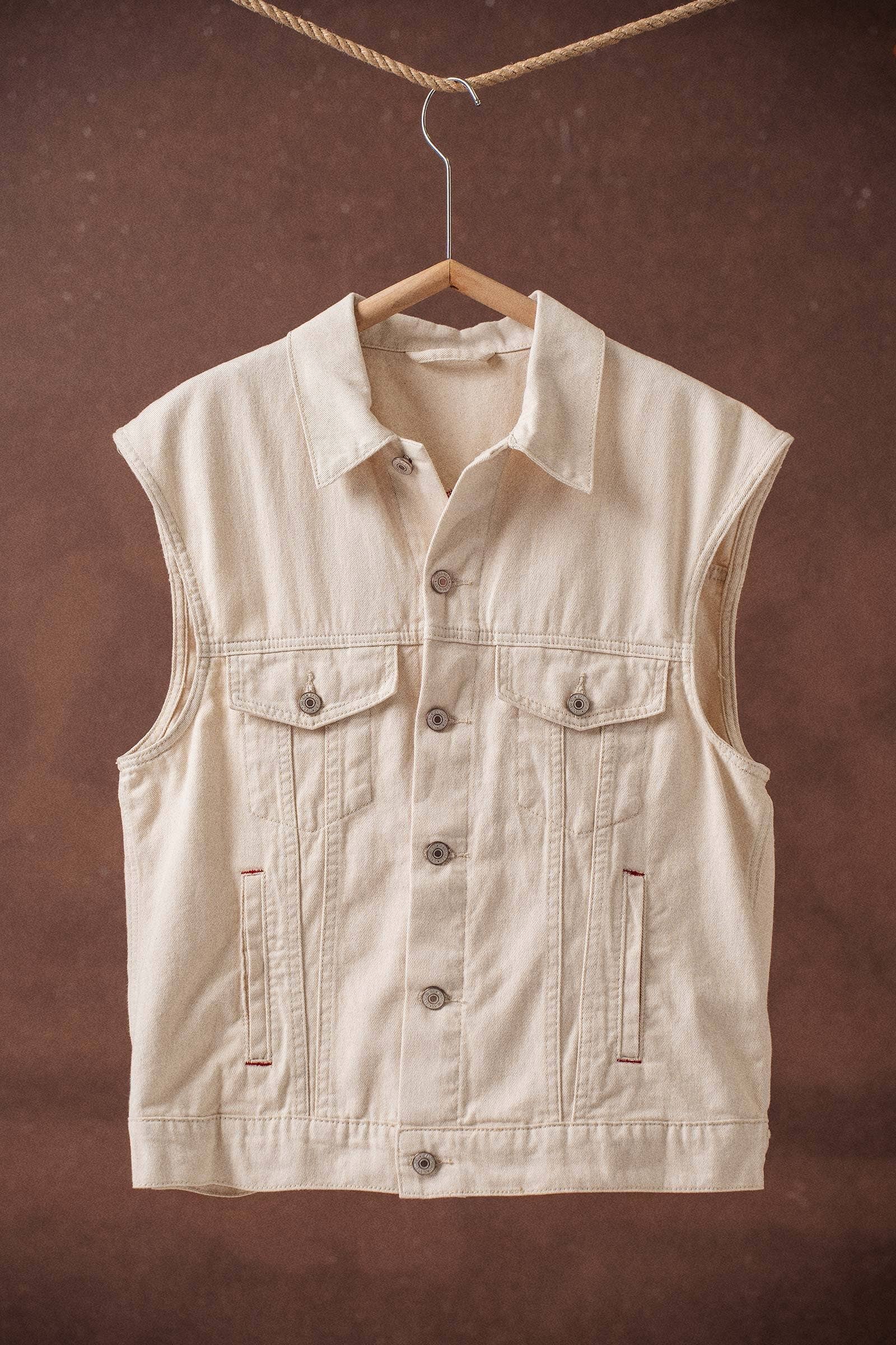Beige vest hanging on a wooden hanger against a brown background