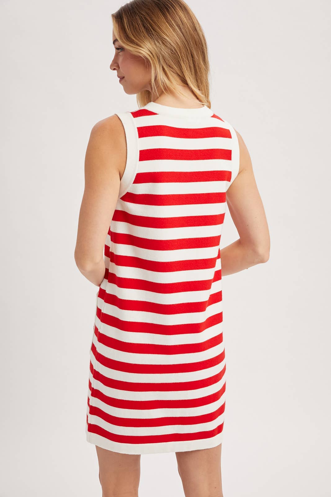 Woman wearing a red and white striped dress against a plain background showing back view.