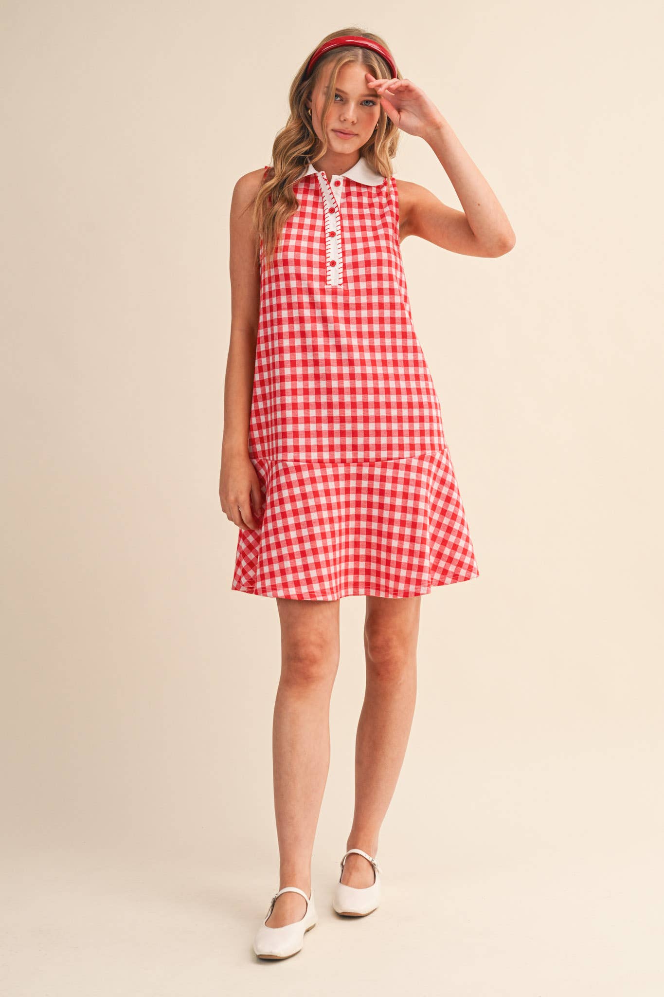 Woman wearing a red and white checkered dress on a beige background