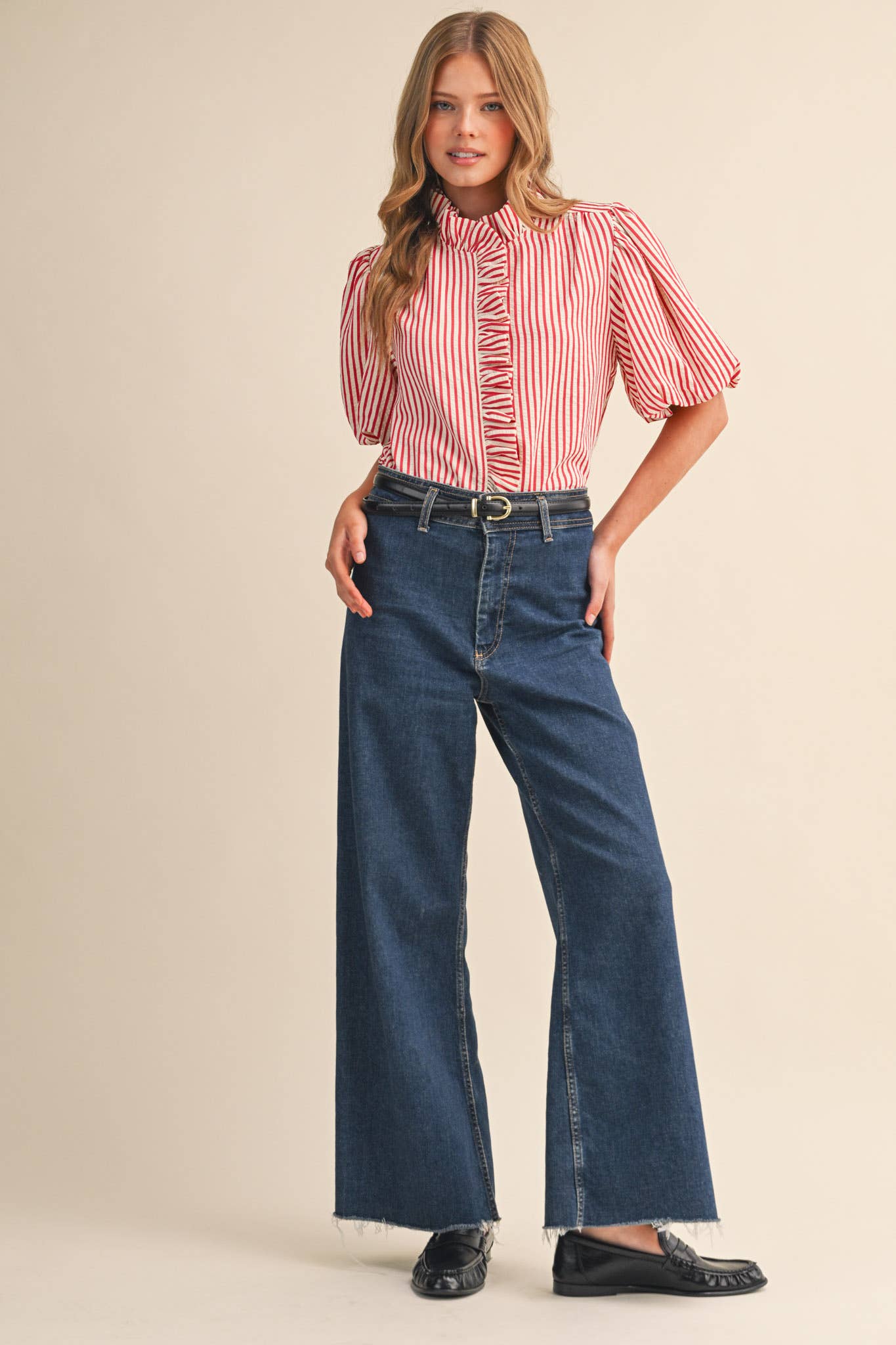 Woman wearing a red and white striped blouse and blue jeans on a beige background
