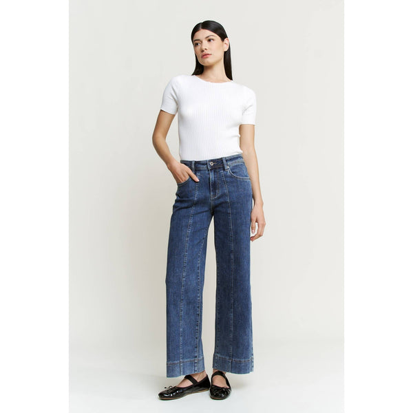 Woman wearing a white t-shirt and blue jeans on a plain background