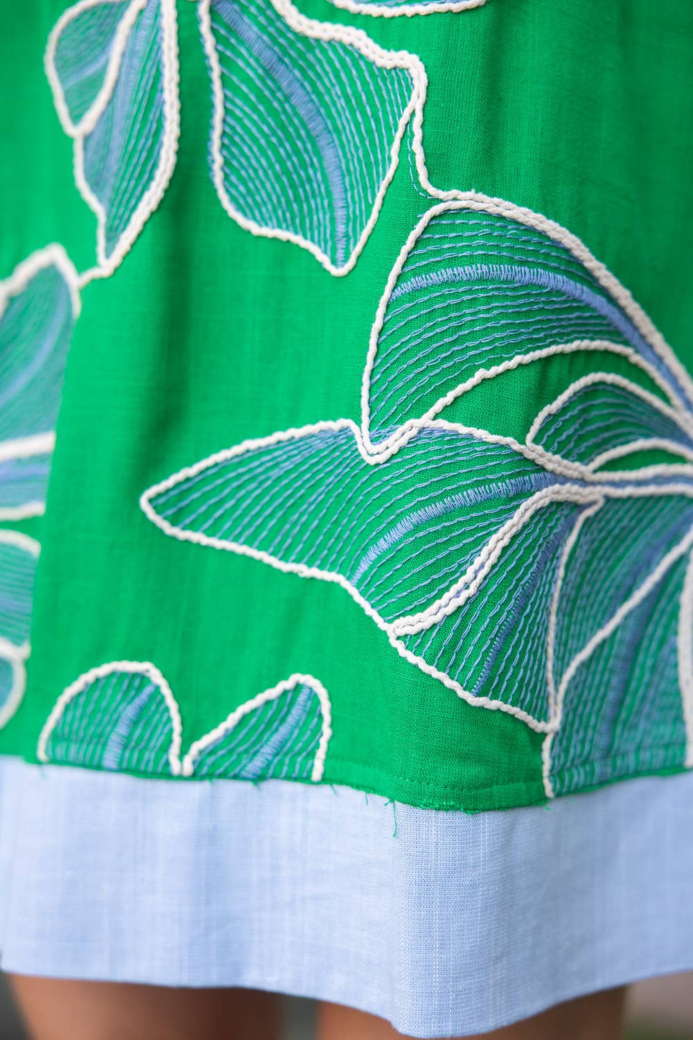 Close-up of a green dress with white floral embroidery