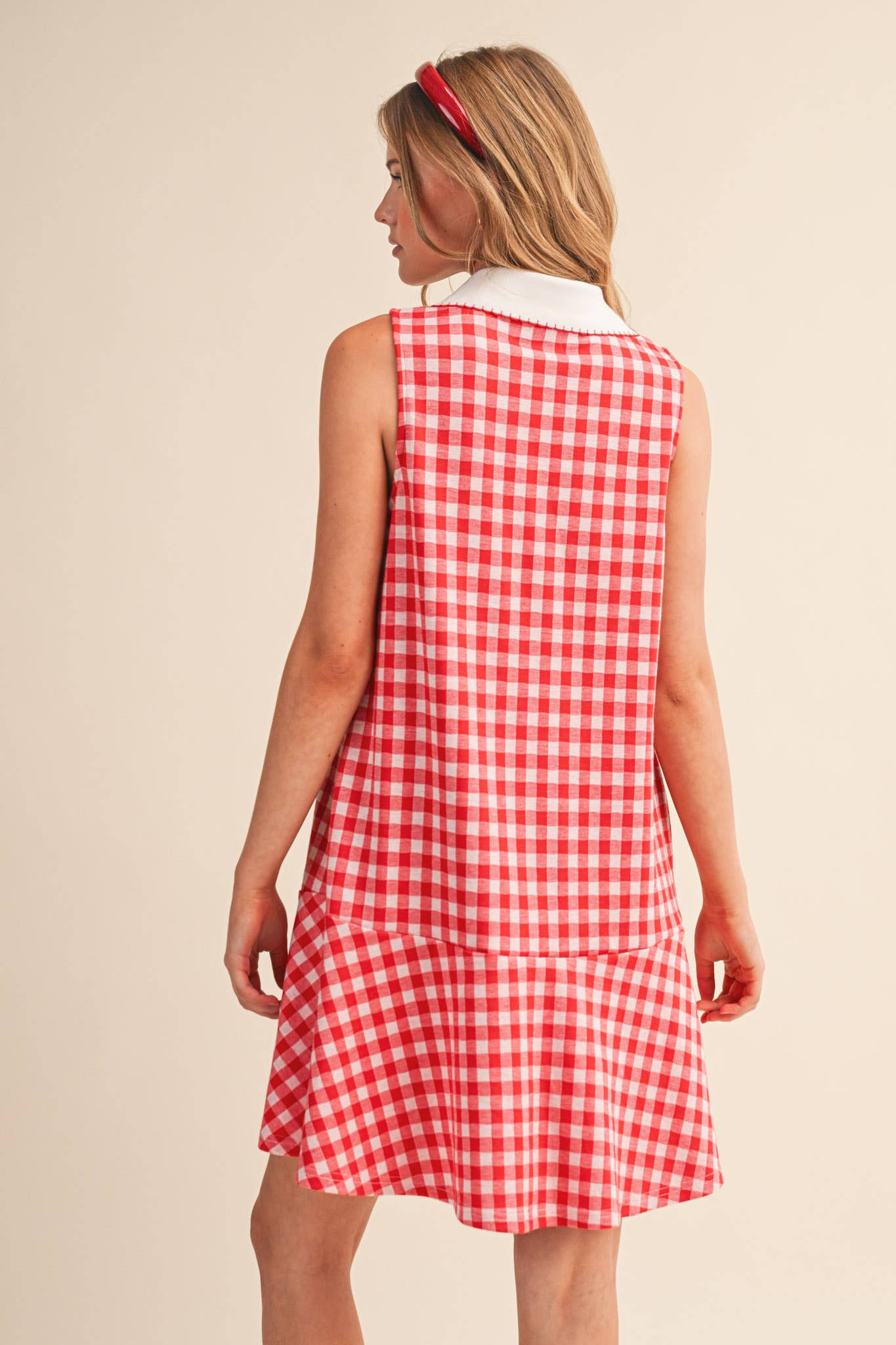 Woman wearing a red and white checkered dress on a beige background