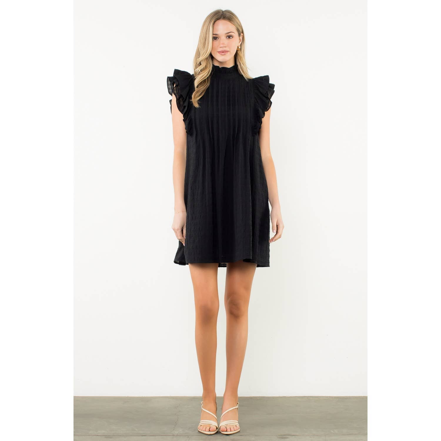 Woman wearing a black dress with ruffled sleeves on a white background