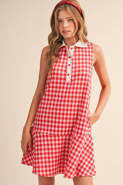 Woman wearing a red and white checkered dress with a white collar on a beige background