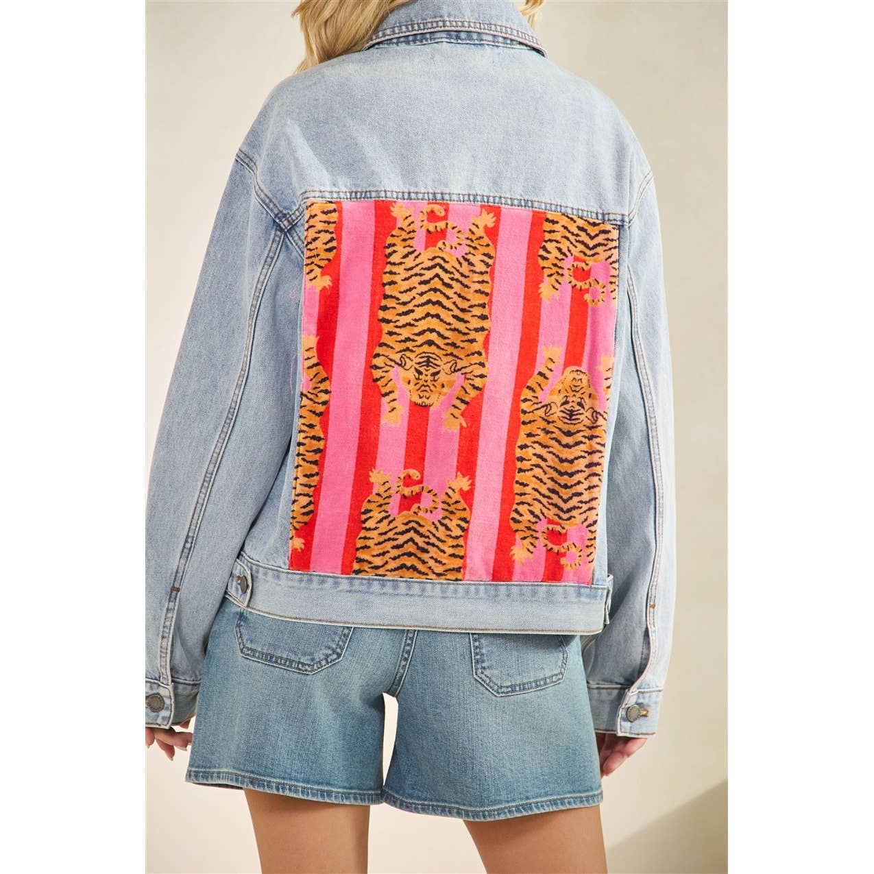 Denim jacket with a colorful tiger pattern on a plain background
