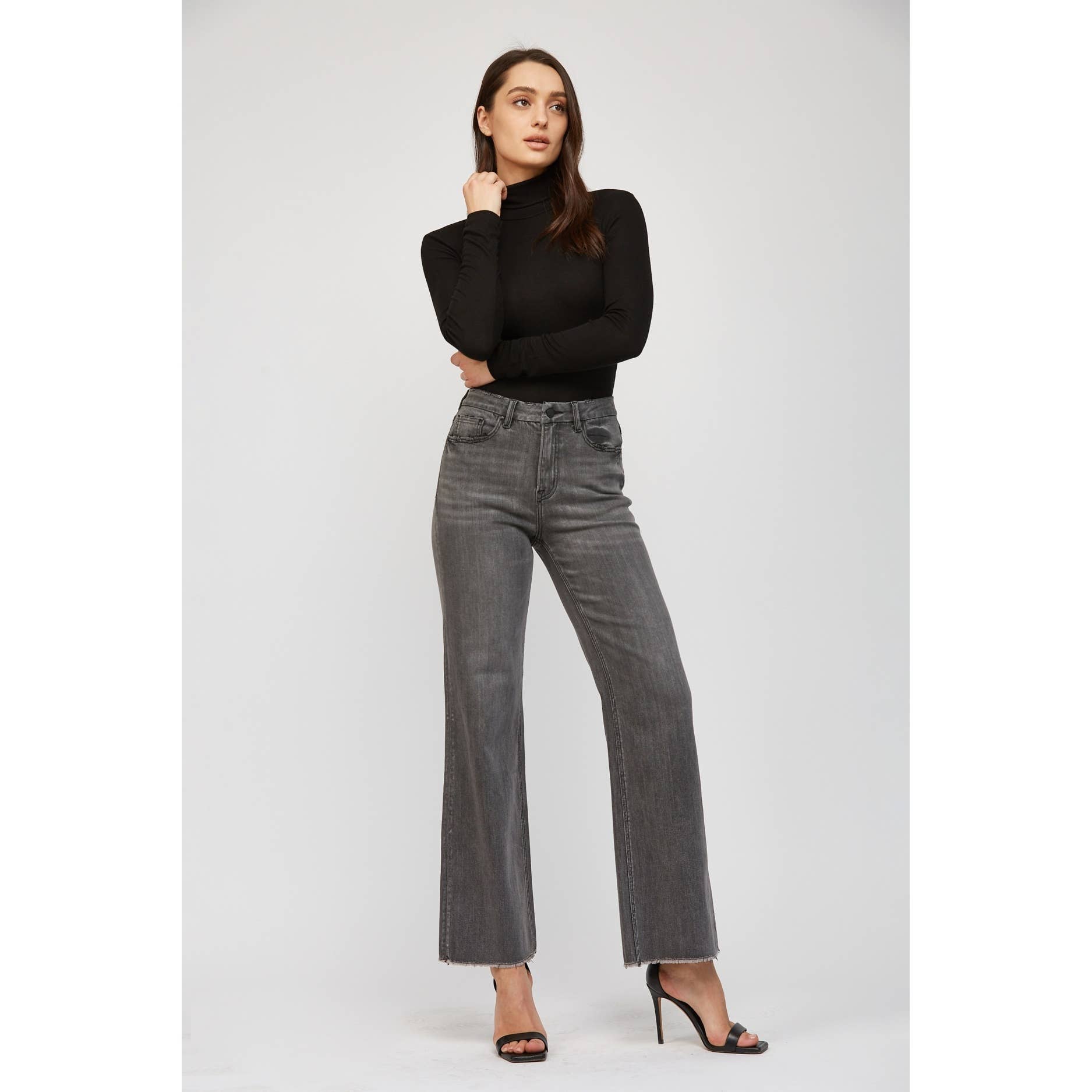 Woman wearing a black turtleneck and gray jeans on a white background