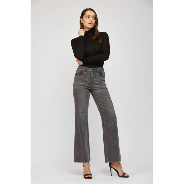 Woman wearing a black turtleneck and gray jeans on a white background