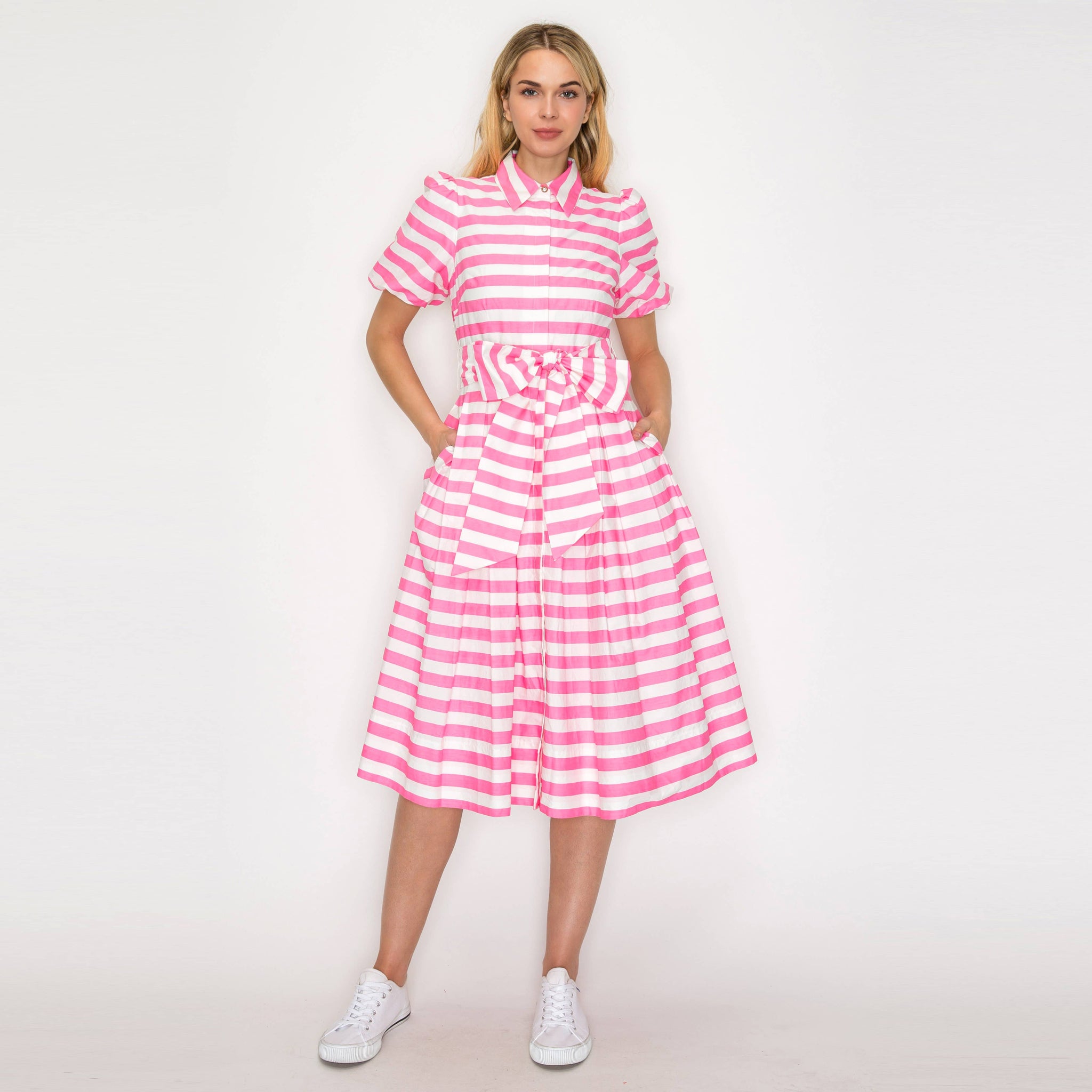 Woman wearing a pink and white striped dress on a white background; front view.