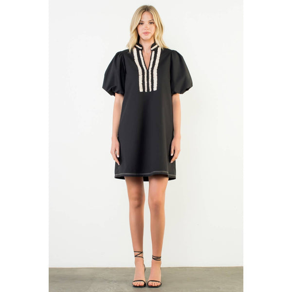 Woman wearing a black dress with white trim on a white background