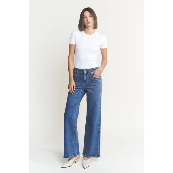 Woman wearing a white t-shirt and medium blue jeans on a plain background