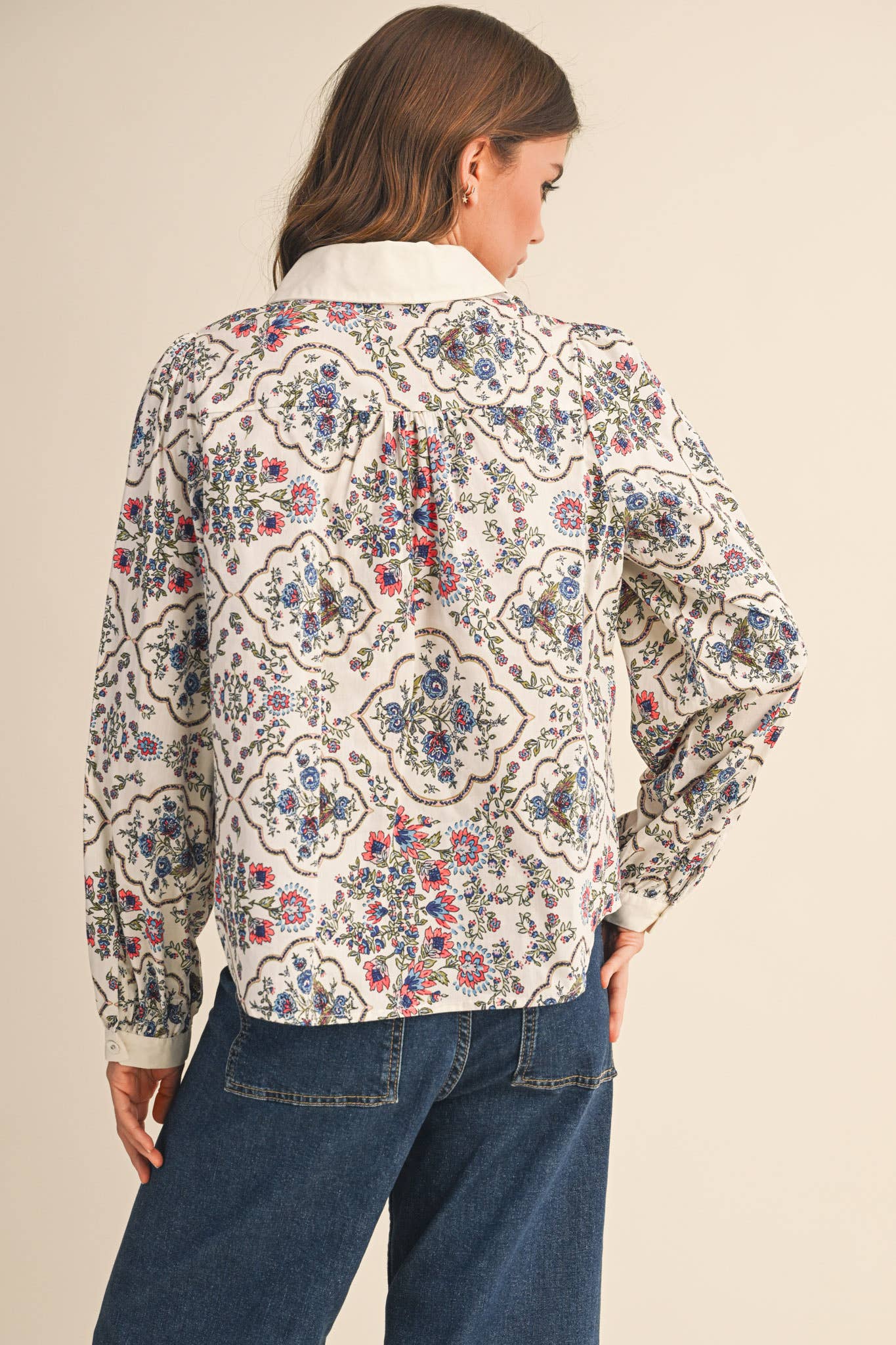 Woman wearing a floral patterned blouse with a beige background