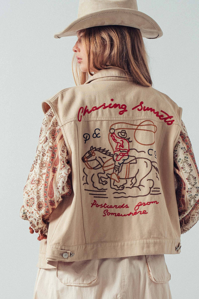 Person wearing a beige vest with embroidered text and graphics on a plain background