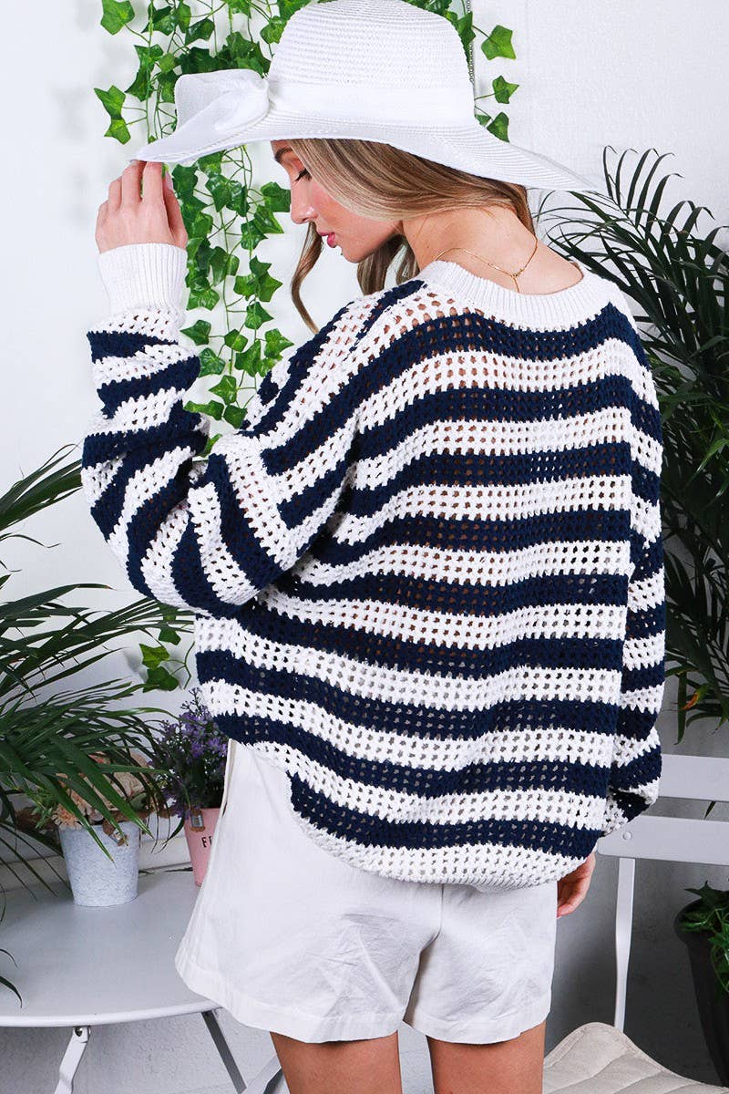 Person wearing a striped sweater and white hat indoors with plants in the background showing back view.