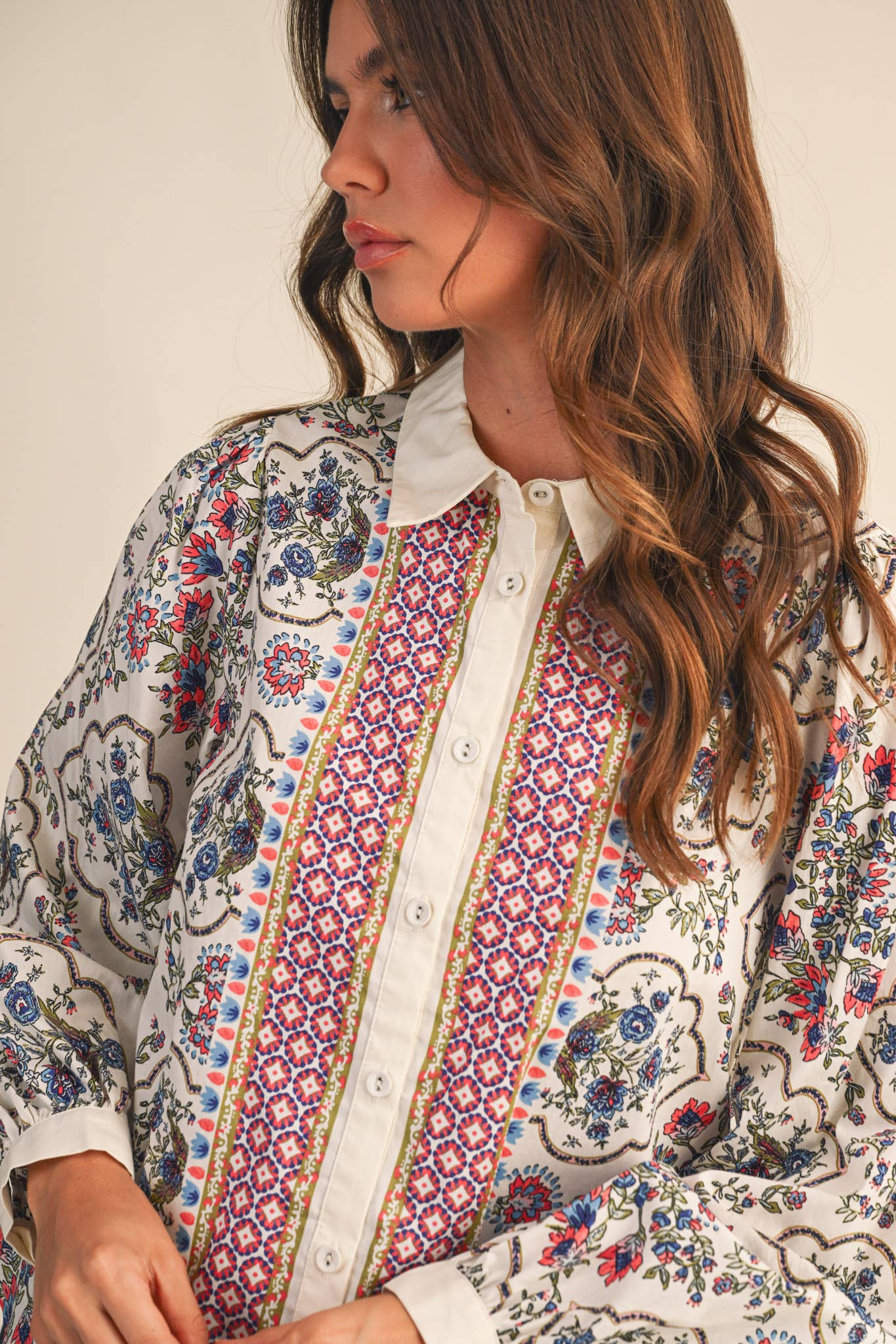 Woman wearing a colorful patterned shirt with a neutral background