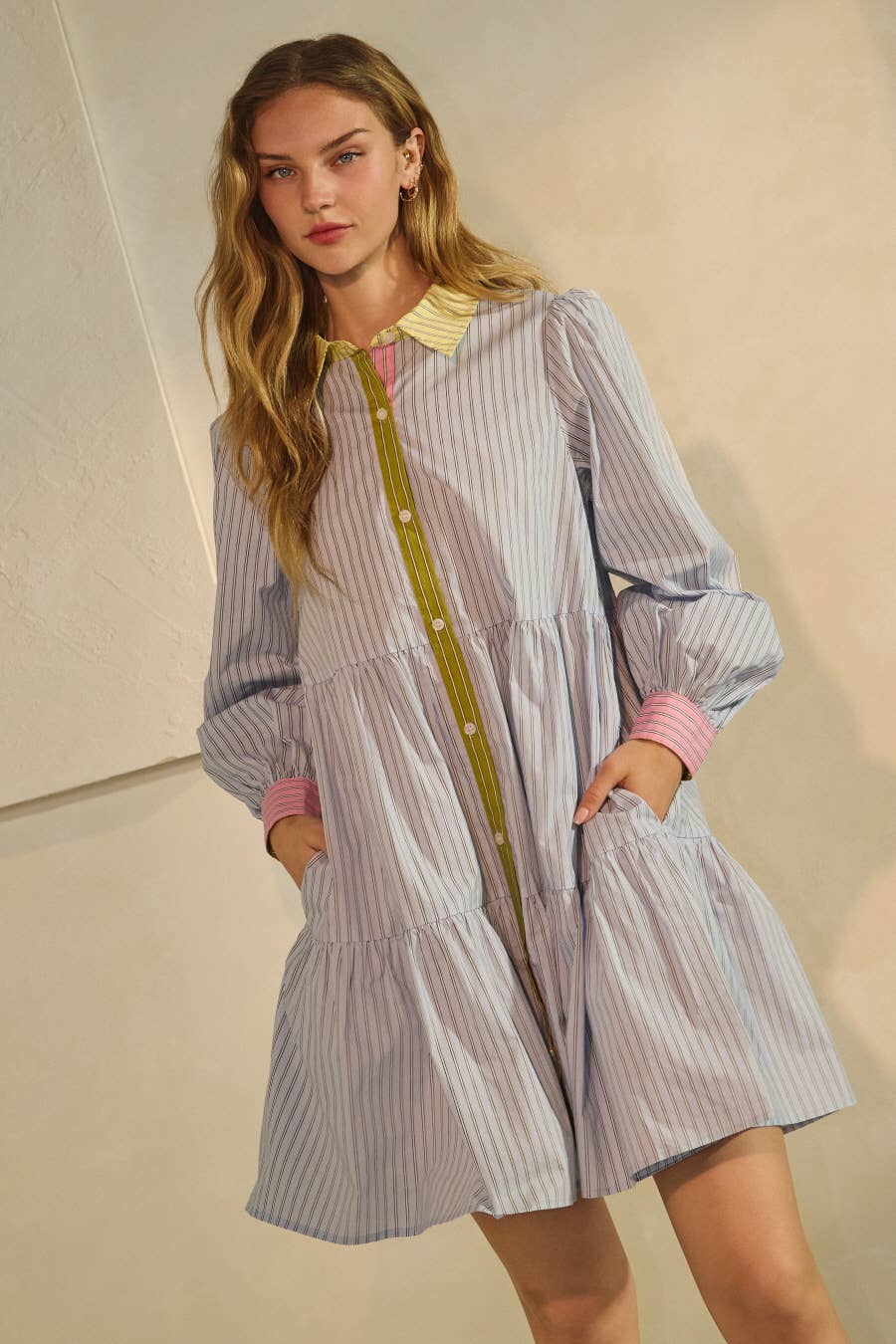 Woman wearing a striped dress with a yellow belt against a neutral background