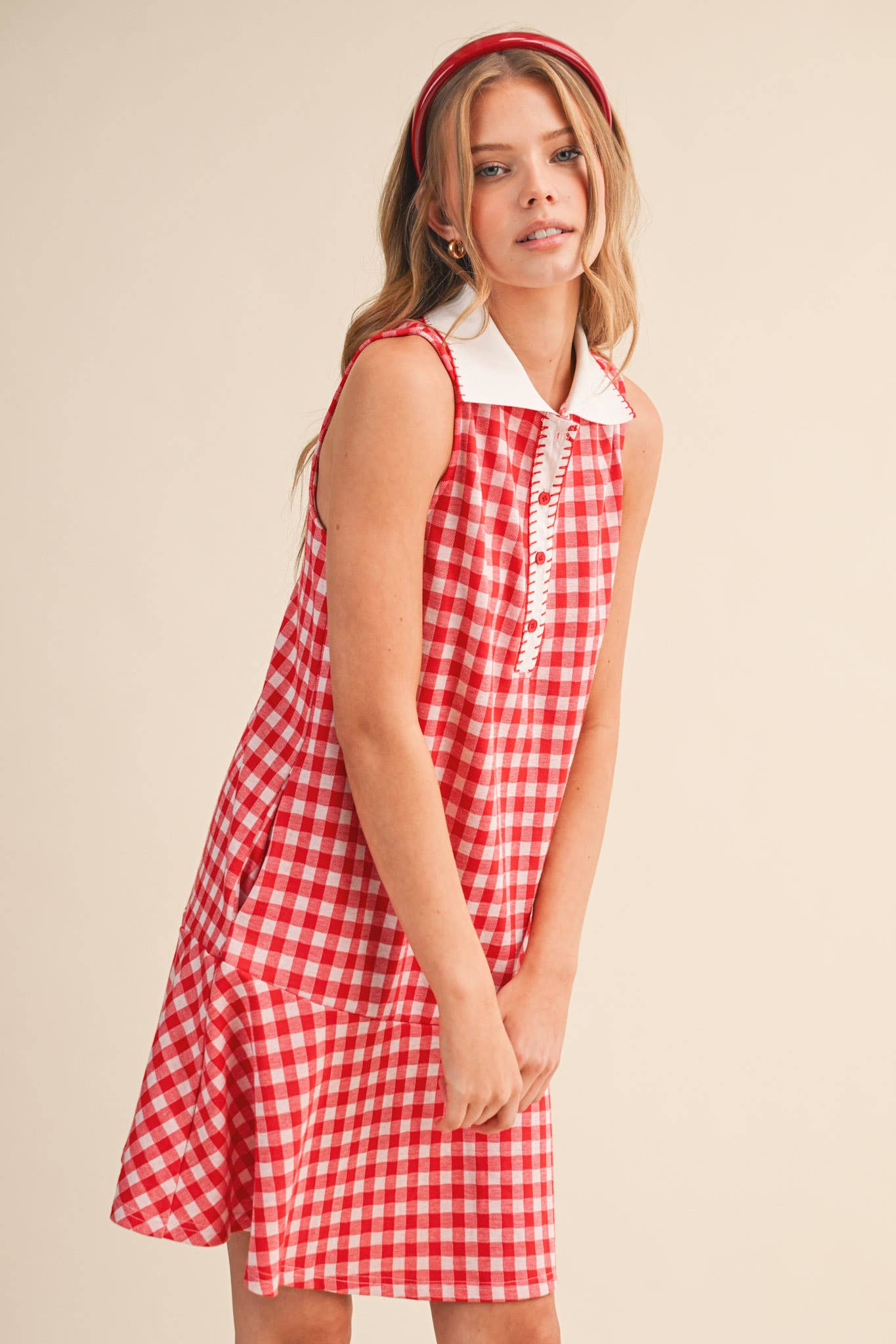 Woman wearing a red and white checkered dress against a beige background