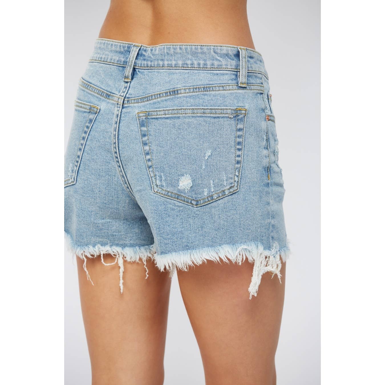 Denim shorts with frayed hem on a plain background