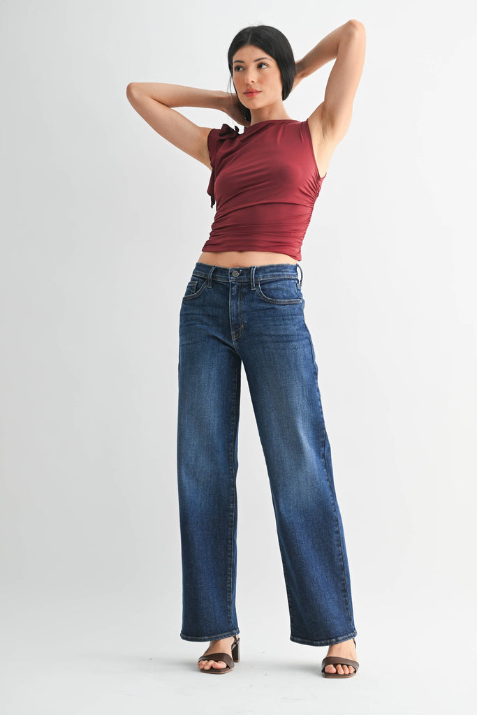 Woman wearing a red top and blue jeans on a white background. Full front view.