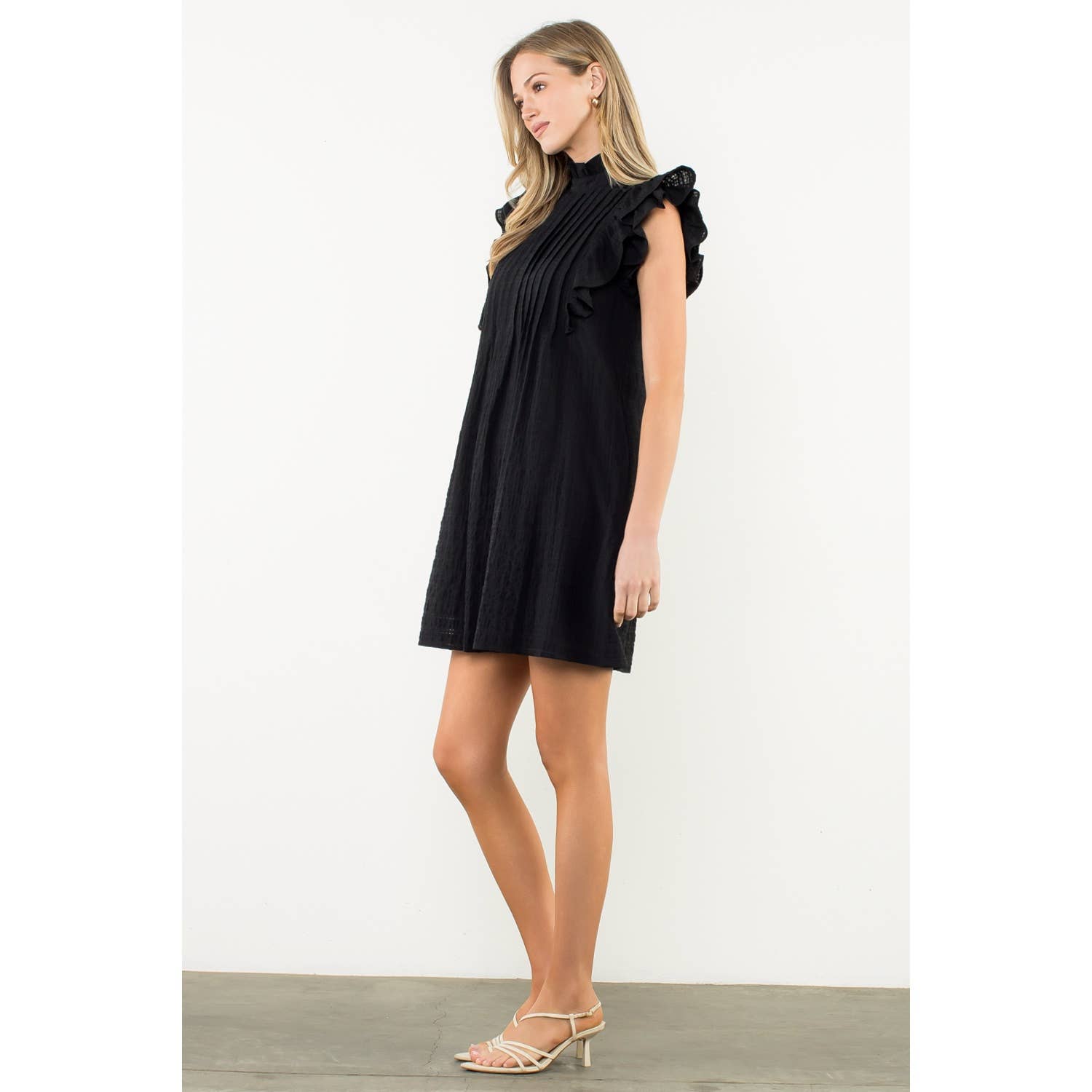 Woman wearing a black dress with ruffled sleeves on a white background