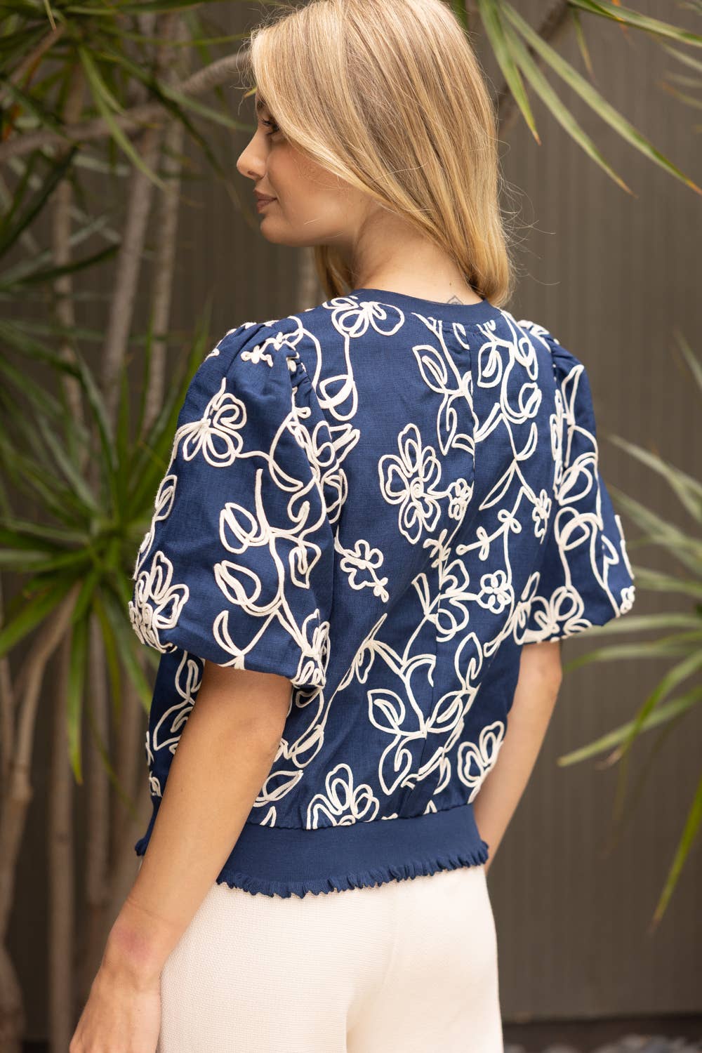 Woman wearing a blue floral blouse with plants in the background