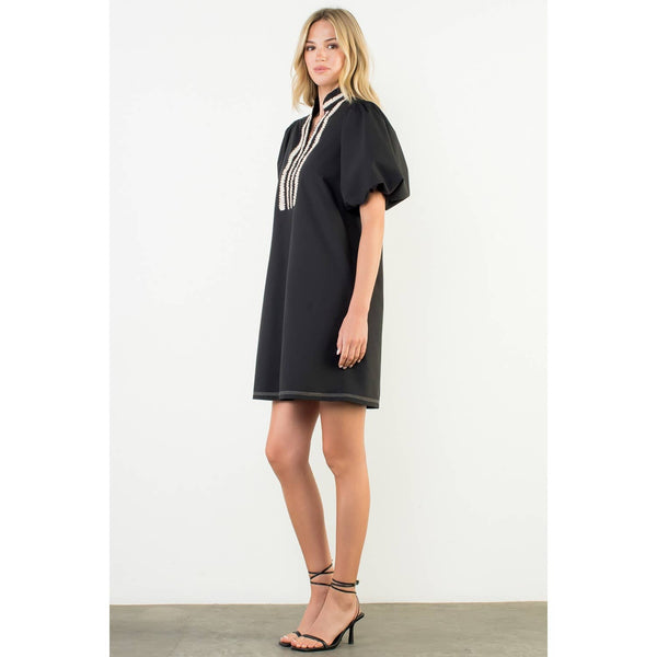 Woman wearing a black dress with white trim on a white background