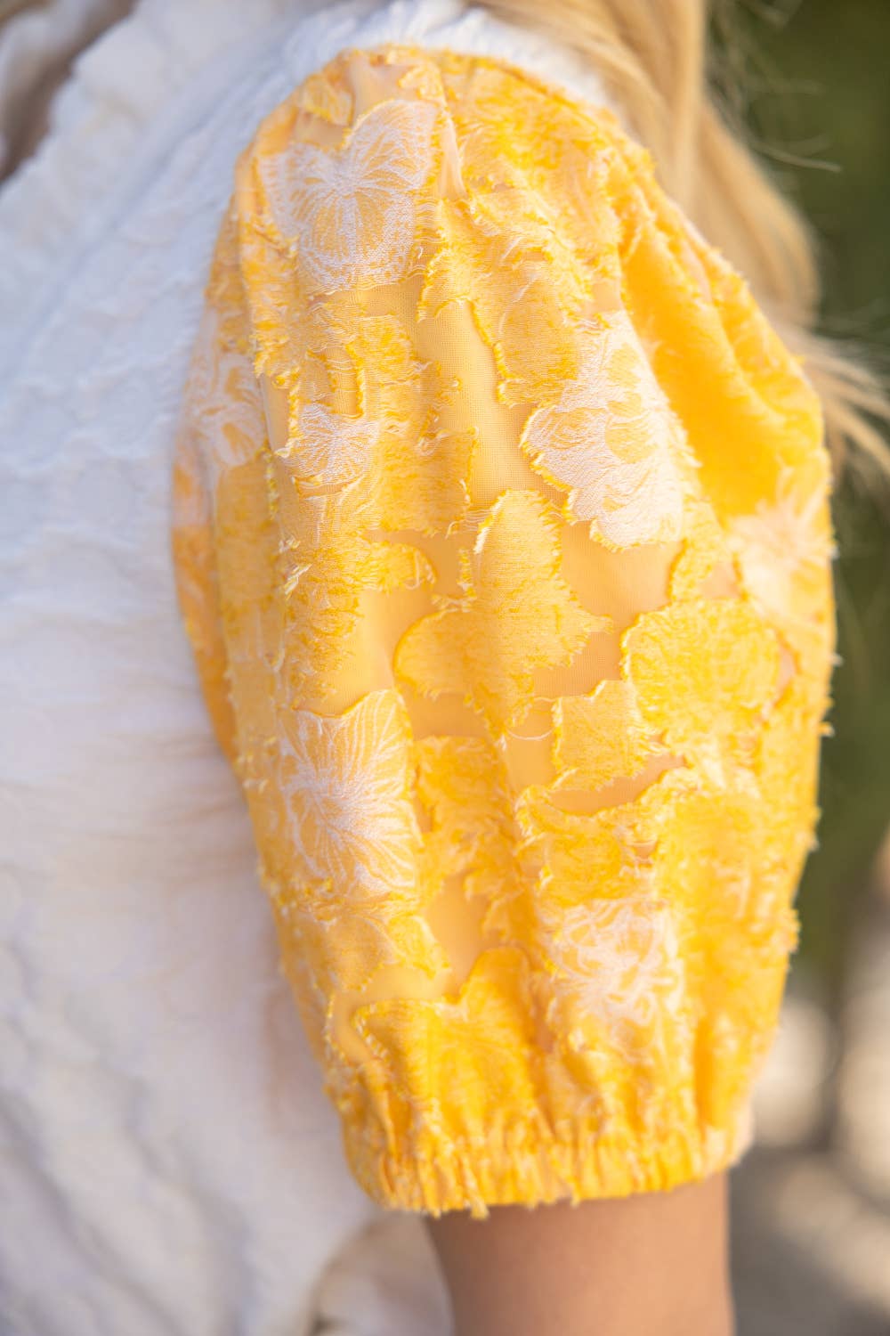 Close-up of a yellow textured garment with floral patterns on a blurred background
