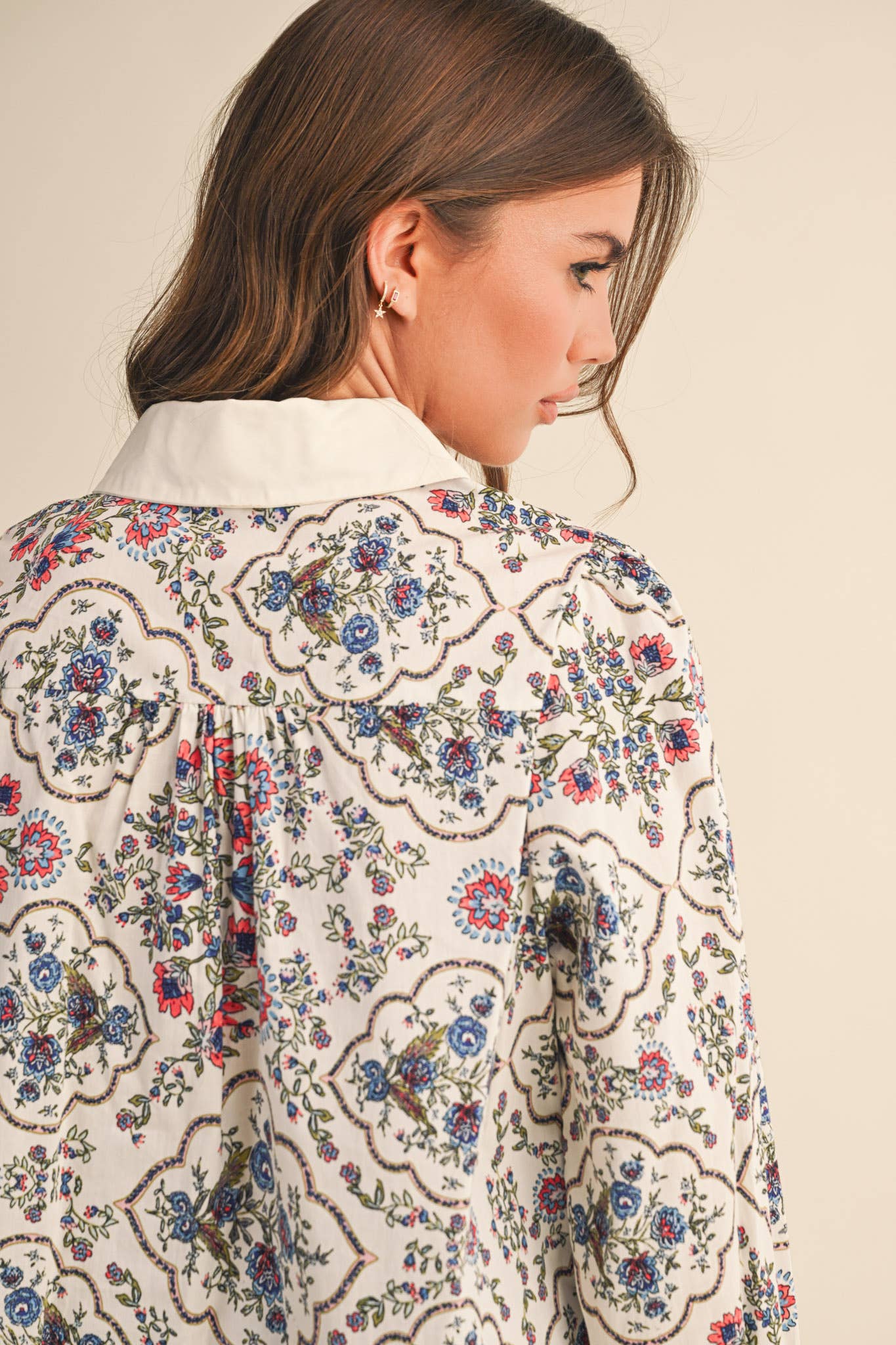 Woman wearing a floral patterned blouse with a neutral background